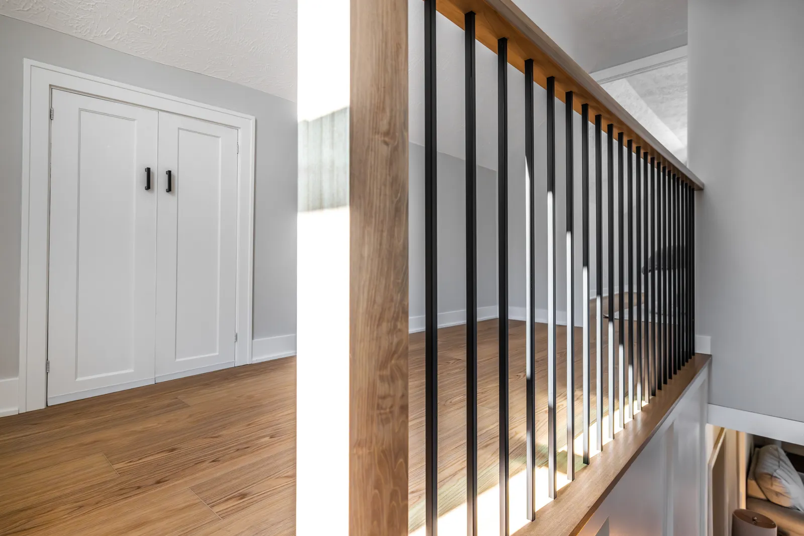 Hallway with closet doors and railing viewed from bedroom